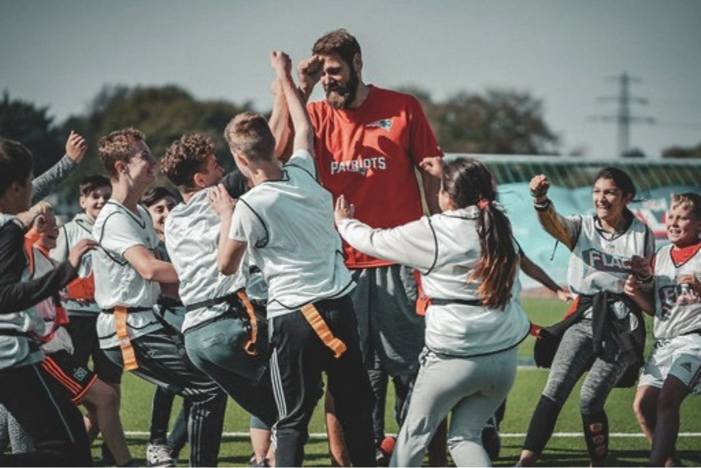 Sebastian Vollmer klatscht beim Flag-Football-Camp mit jubelnden Kindern ab