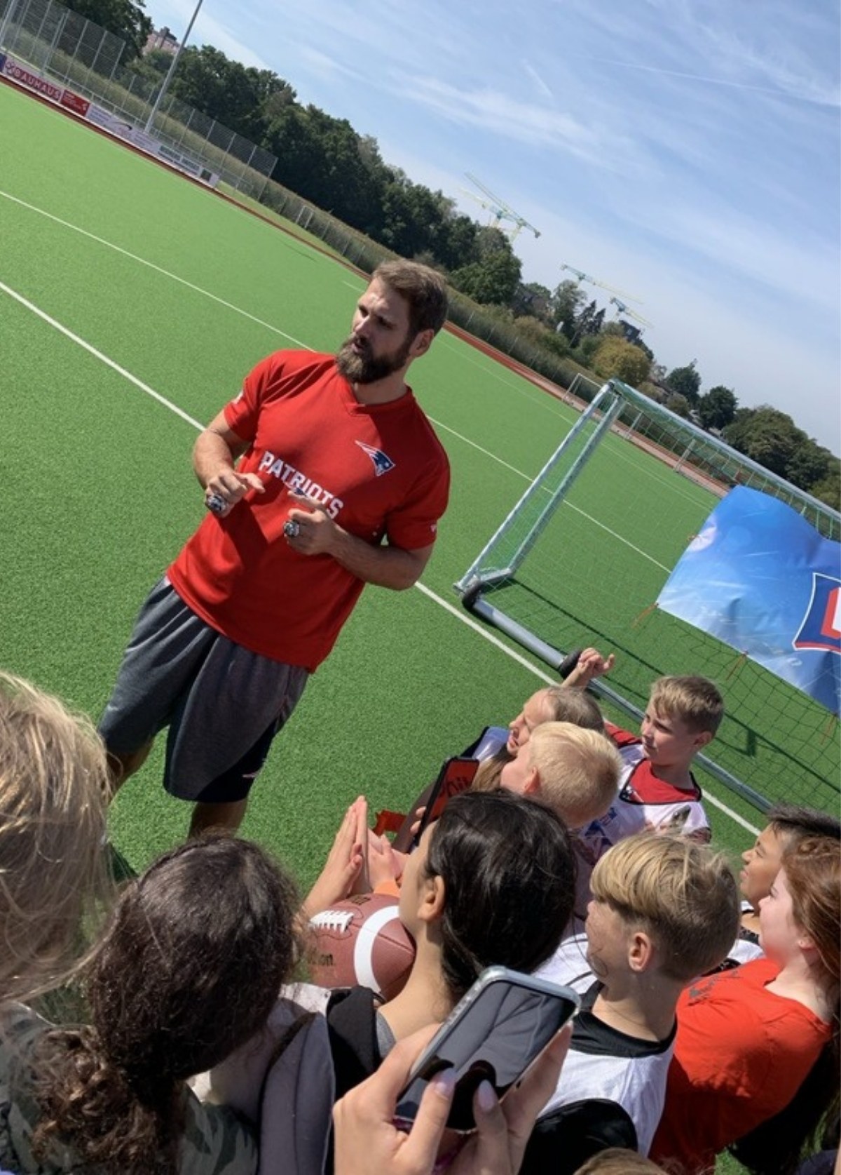 Sebastian Vollmer im Patriots-Shirt zeigt Kindern beim Flag-Football-Camp seine Super-Bowl-Ringe