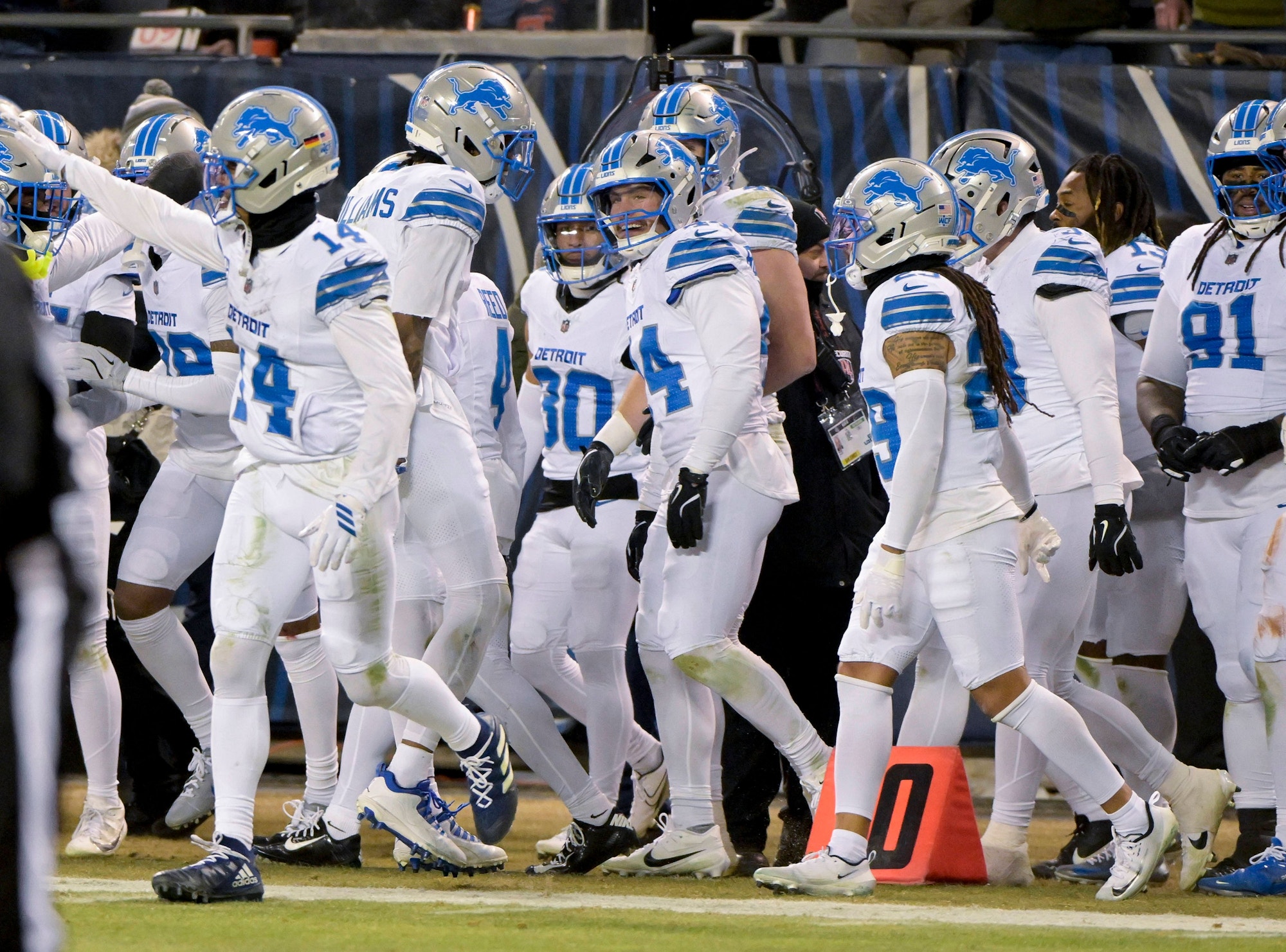 Spieler der Detroit Lions in weißen Trikots jubeln gemeinsam an der Seitenlinie