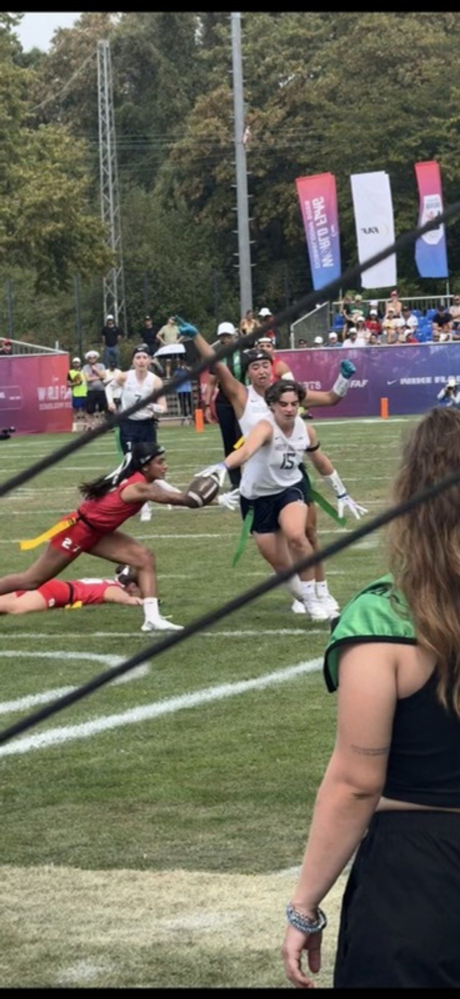 Spielszene aus dem Frauenturnier der Flag-Football-WM 2026 in Düsseldorf: Eine Spielerin in Rot hechtet nach einer Gegenspielerin in Weiß mit Ball