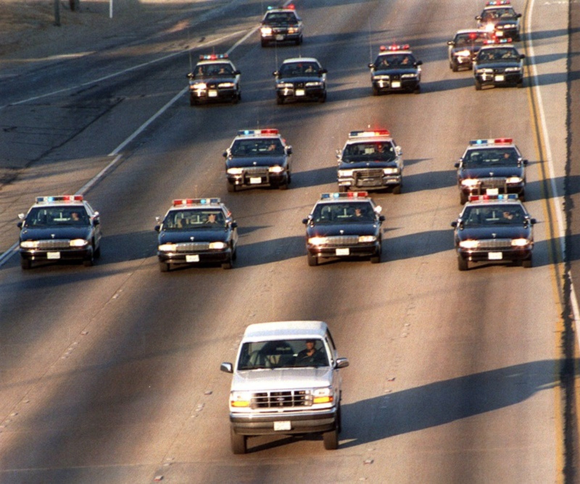 Der weiße Ford Bronco fährt auf dem Freeway, dahinter eine Kolonne von Polizeiwagen