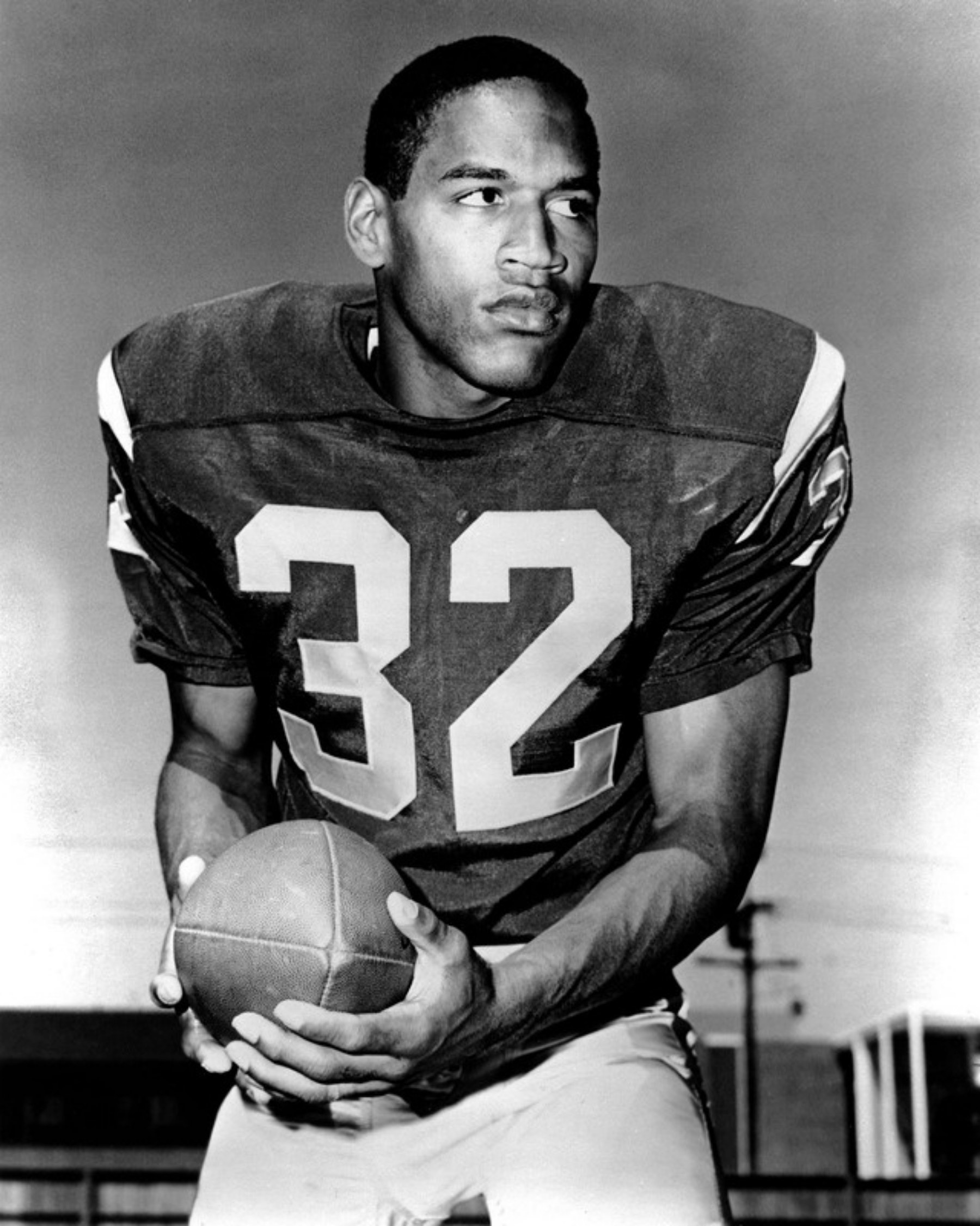 Junger O.J. Simpson im Trikot mit der Nummer 32 hält einen Football