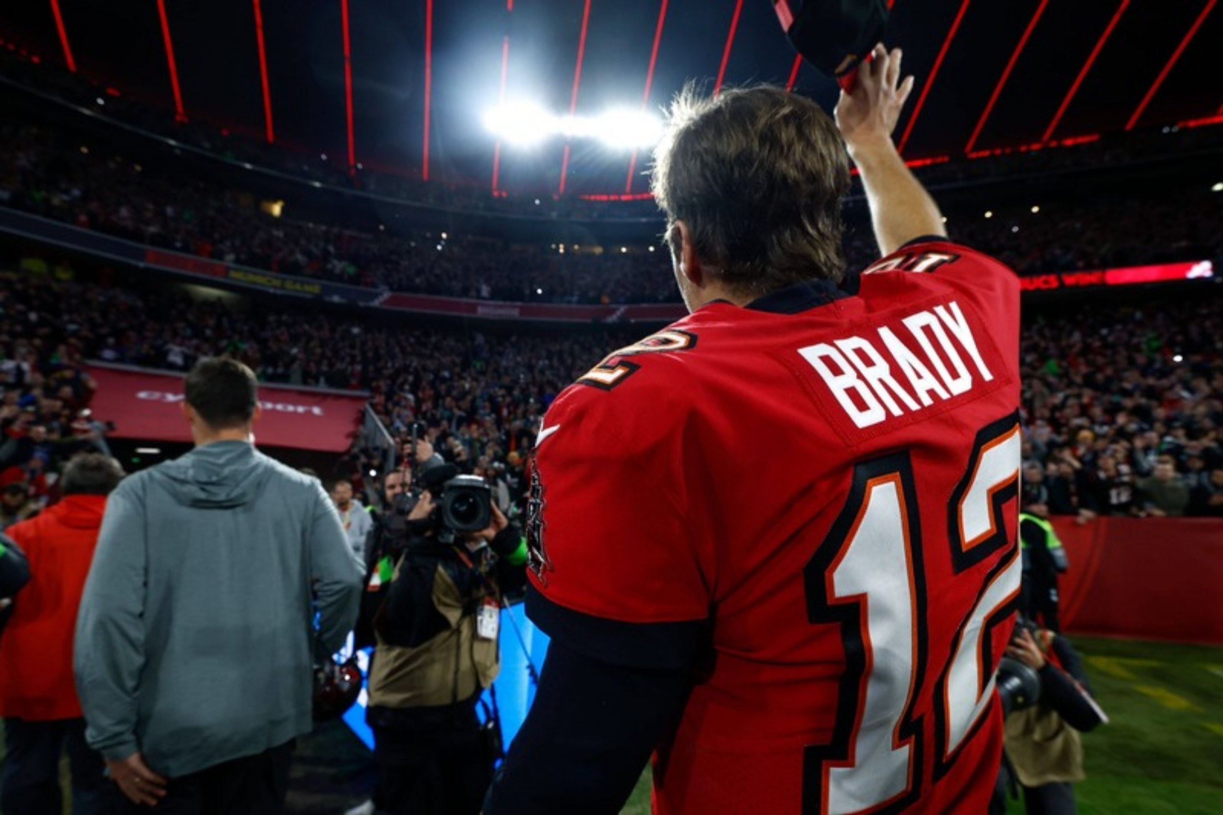 Tom Brady im roten Buccaneers-Trikot winkt in der Allianz Arena München den Fans zu
